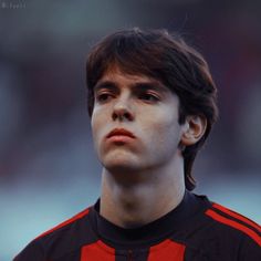 a close up of a soccer player wearing a black and red uniform with his eyes closed