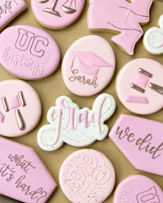 decorated cookies with pink and white icing are arranged on a brown surface, including the word congratulations