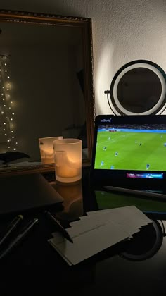 a laptop computer sitting on top of a desk next to a mirror and lit candle