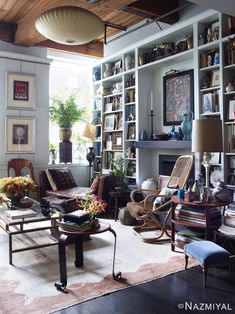 a living room filled with lots of furniture and bookshelves next to a fire place