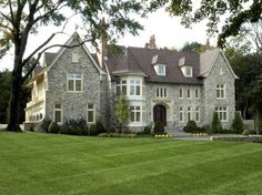 a large stone house sitting on top of a lush green field