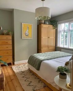 a bed room with a neatly made bed next to a window and a wooden dresser