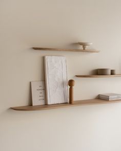 two shelves with books and other items on them in a white walled room, one is empty