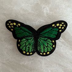 a green and yellow butterfly sitting on top of a white surface