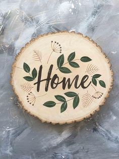 a wooden sign with the word home painted on it's side and green leaves