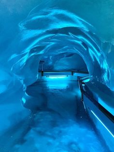 the inside of an ice cave with benches and blue lights on it's walls