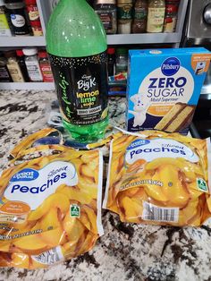 three packages of peaches and two bottles of soda on a counter