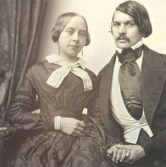 an old black and white photo of two people sitting next to each other in formal dress