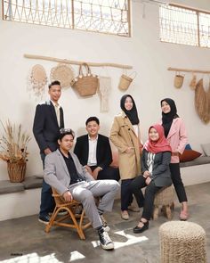 a group of people sitting next to each other in front of a wall with baskets on it