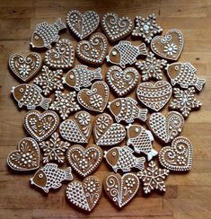 a bunch of cookies that are sitting on a wooden table in the shape of hearts