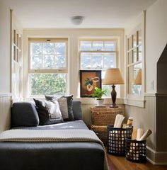 a living room filled with furniture next to two windows and a lamp on top of a table