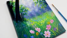 an artist's notebook with colorful flowers and trees painted on the cover, next to a paintbrush