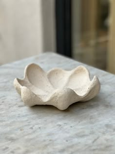 a small white bowl sitting on top of a marble table next to a window sill