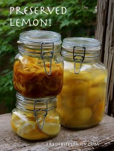 two jars filled with lemons sitting on top of a wooden table