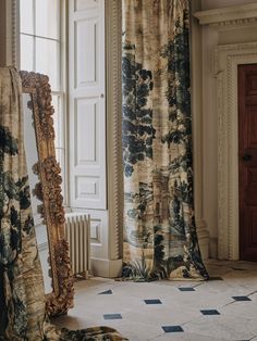 the curtains are hanging in front of an ornate mirror on the floor next to a window