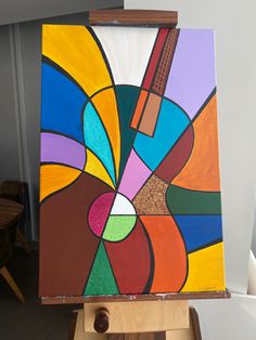 an abstract painting is displayed on a wooden easel