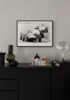 a black and white photo hanging on the wall next to a dresser with liquor bottles