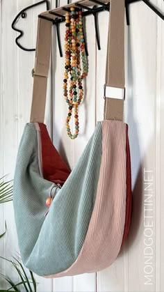 two purses hanging from hooks on a wall