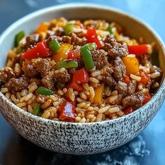 a bowl filled with rice and meat on top of a blue countertop next to a fork