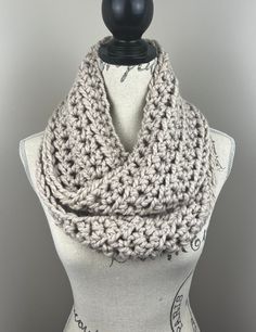 a white mannequin wearing a gray crochet scarf