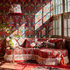 the sun shines through the windows onto a colorfully patterned couch and ottoman in an otherwise empty room