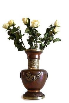 a vase filled with white roses sitting on top of a table