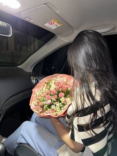 a woman holding a plate with flowers on it in the back seat of a car