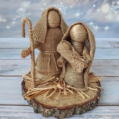 two burlap nativity figurines sitting on top of a piece of wood