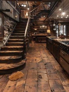 a kitchen with wooden floors and stairs leading up to the second floor in an old log cabin