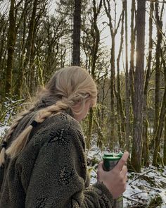 a woman standing in the snow holding a cup