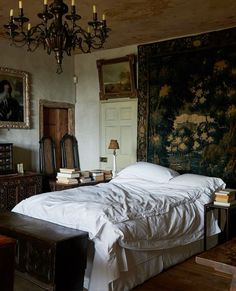 a bedroom with a bed, chandelier and pictures on the wall above it