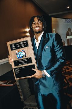 a man in a suit holding up an award plaque