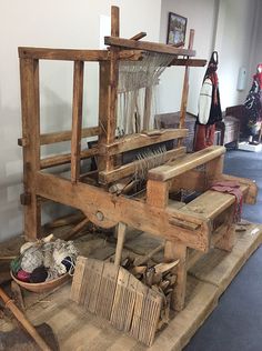 an old weaving machine sitting on top of a wooden table next to other items in a room