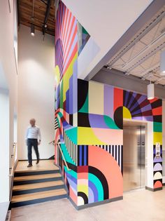 a man is walking down the stairs in front of a colorful mural on the wall