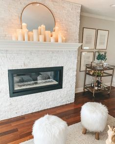 a living room with a fireplace and white fur stools