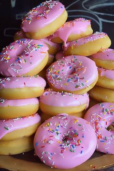 a pile of doughnuts with pink frosting and sprinkles on them