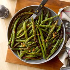 green beans in a pan with a knife on the side and napkin next to it