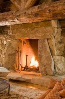 a living room with a fire place in the center and stone walls on both sides