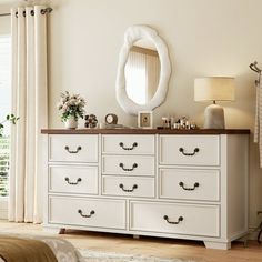 a white dresser sitting next to a bed in a bedroom