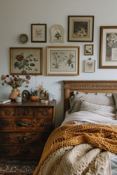 a bedroom with pictures on the wall and a bed covered in a blanket next to a dresser