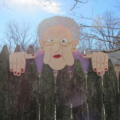 an old woman's head sticking out of the top of a wooden picket fence