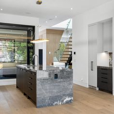 a kitchen with an island in the middle of it and stairs leading up to the second floor