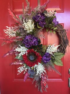 a wreath with purple and red flowers is hanging on the front door's red door