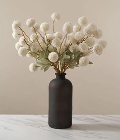 a black vase with white flowers in it