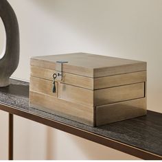 a wooden box sitting on top of a table next to a metal object with a key in it