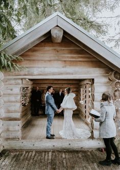 a couple getting married in front of a log cabin