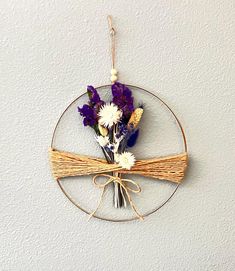 a metal circle with flowers hanging from it's side on a white wall next to a string