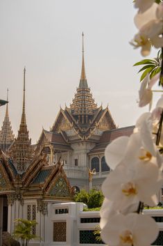 white flowers are in front of a building with gold and silver spires on it