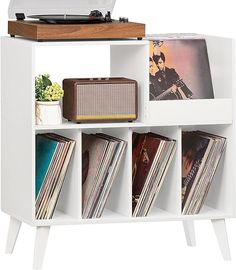 an old record player is sitting on top of a white shelf with records and vinyls