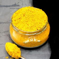 a glass jar filled with yellow powder next to a spoon